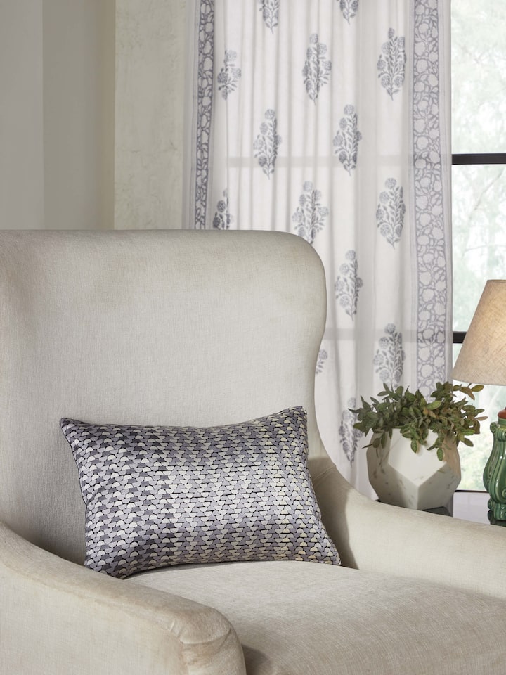 Lifestyle shot of printed grey cushion styled on a neutral-toned sofa.