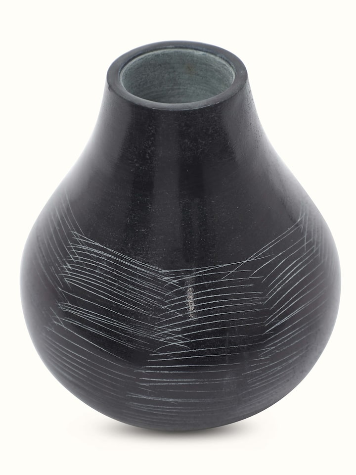 Side angle of carved stone vase in black color highlighting detailed carving and smooth finish