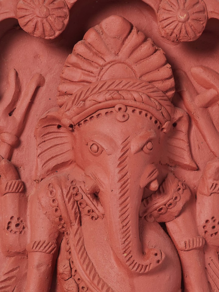 Close-up view of matte terracotta clay Ganesha idol, focusing on the fine details and textures of the clay work.