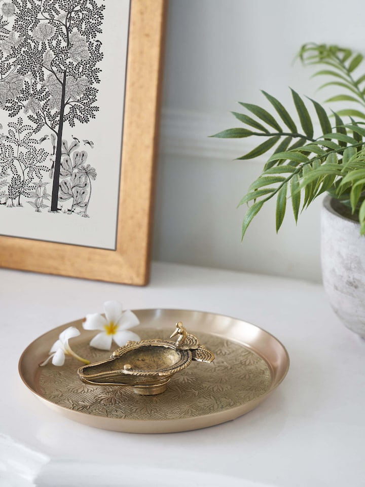 Close-up of the antique brass dhokra peacock diya highlighting its detailed craftsmanship.
