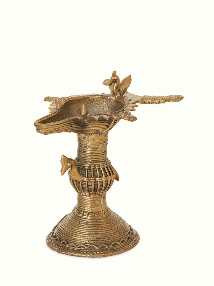 Angled view of antique brass dhokra diya, showcasing its traditional design and ornate details