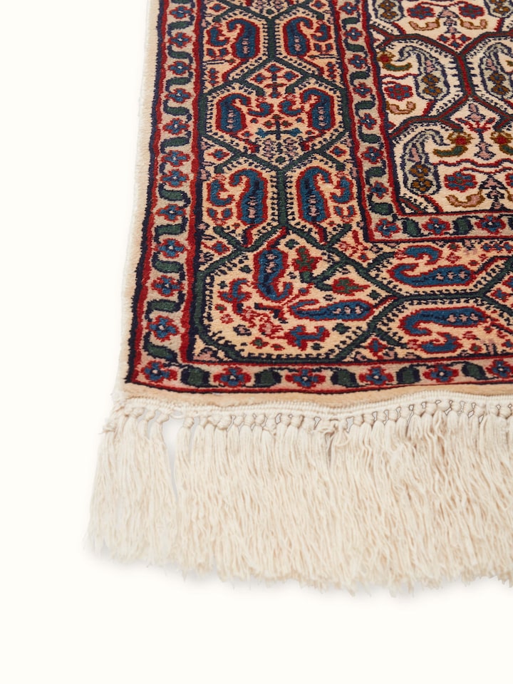 Angled view of a Persian hand-knotted silk carpet from Kashmir, showcasing the detailed craftsmanship and luxurious texture.