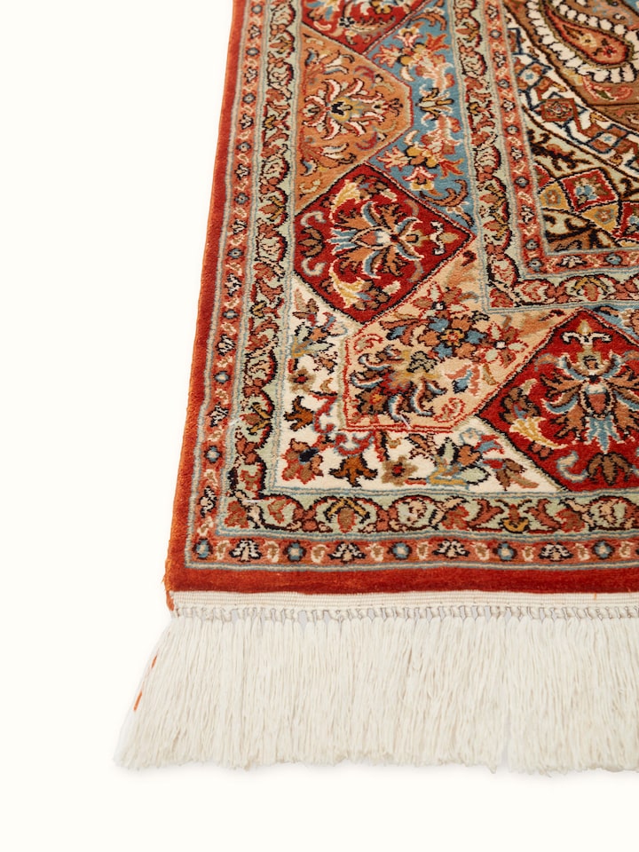 Angled view of Traditional Persian rust khatamband Kashmir silk hand-knotted carpet highlighting its detailed patterns