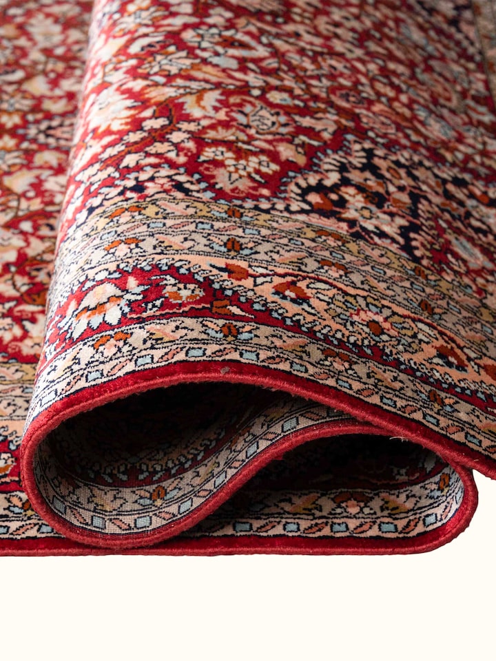 Detail view of Traditional Persian Red Kashan Kashmir Silk Hand-Knotted Carpet highlighting the intricate pattern and pile texture, from a differen...