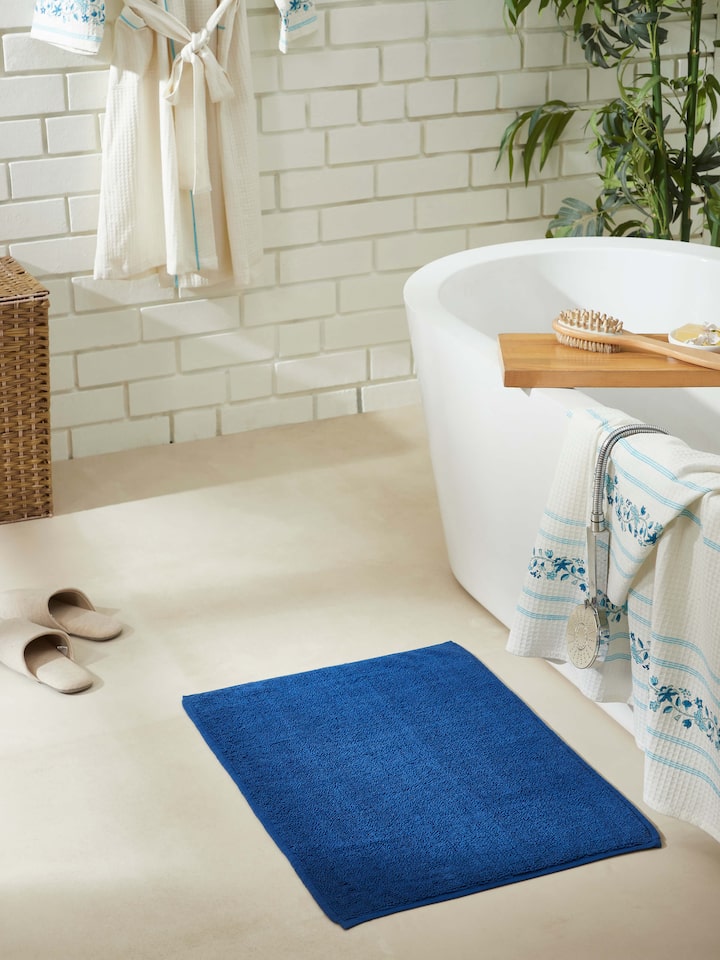 Solid blue cotton bath mat placed in bathroom setting