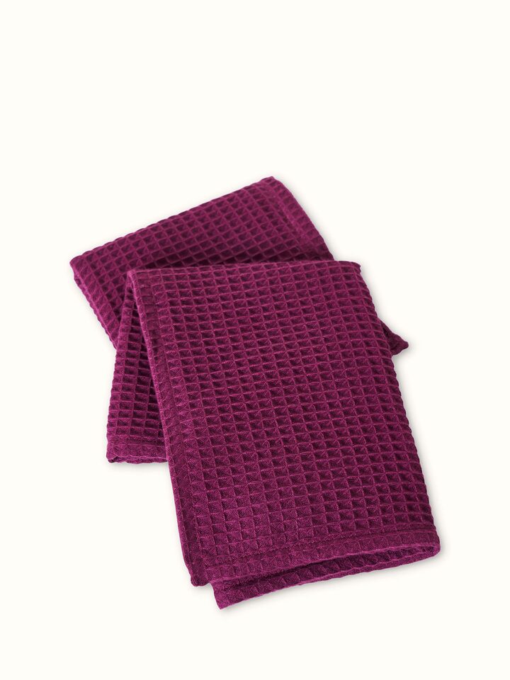 Angled view of Amala solid purple waffle cotton hand towel