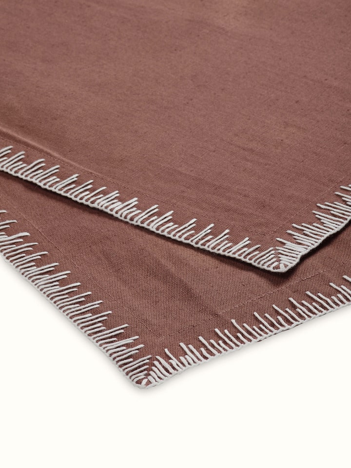 Close-up of hand embroidery and edge stitch detailing on brown table mat