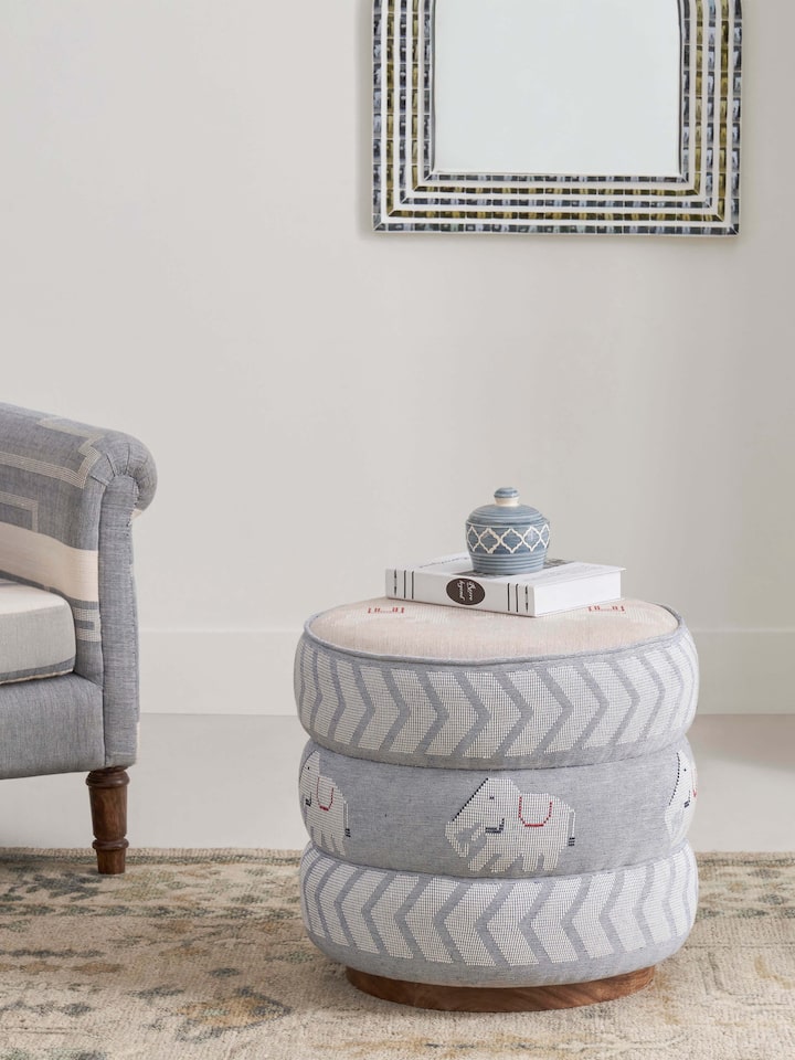 Side view of the Bawan Buti pouffe, highlighting the upholstery and the Sheesham wood frame