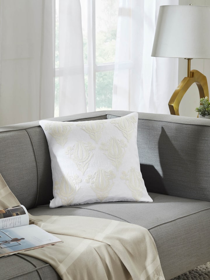 Lifestyle image of embroidered cushion cover styled on a sofa, reflecting artisanal Kashmiri craft.